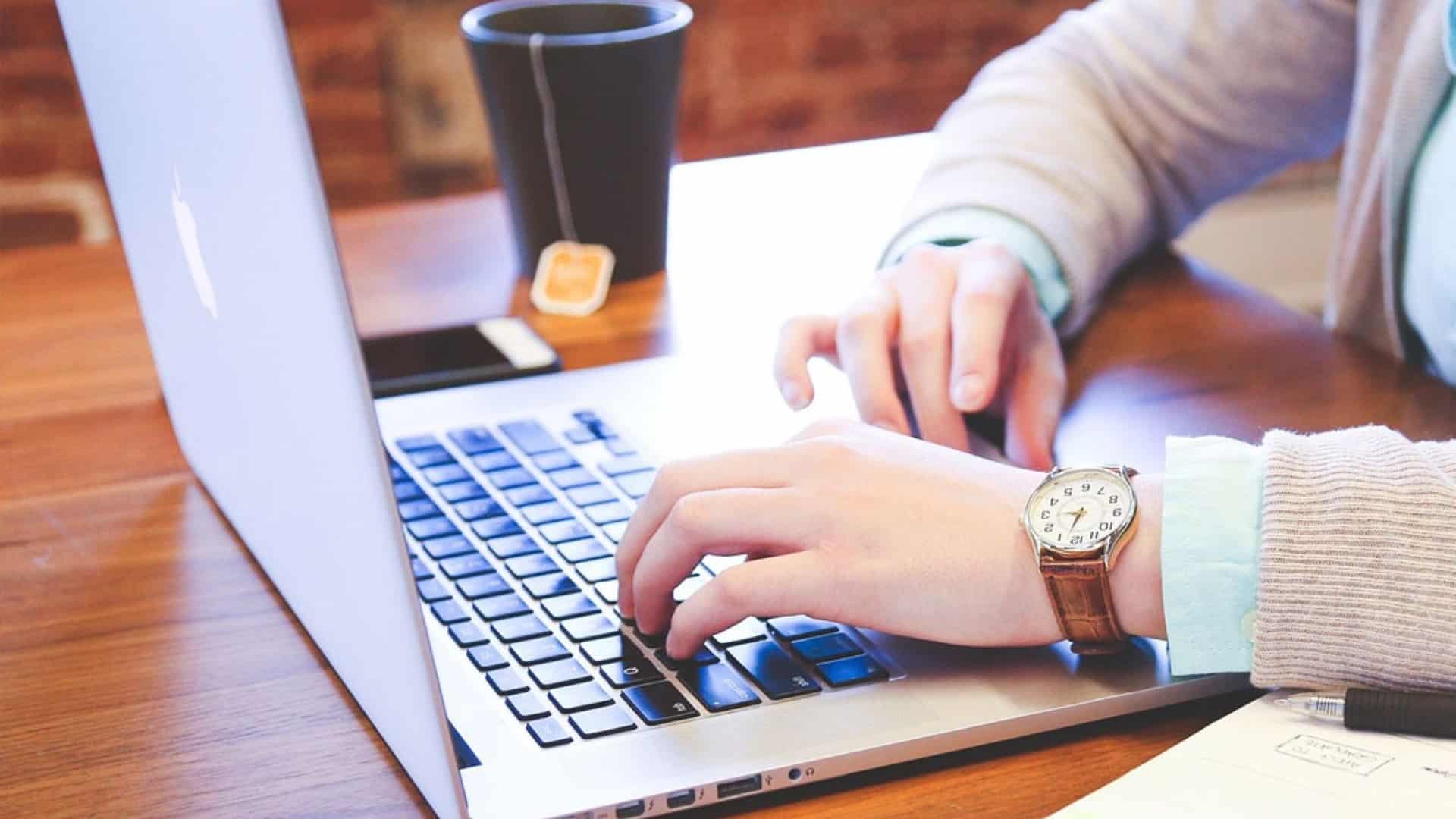 A photo of a man typing on a laptop.