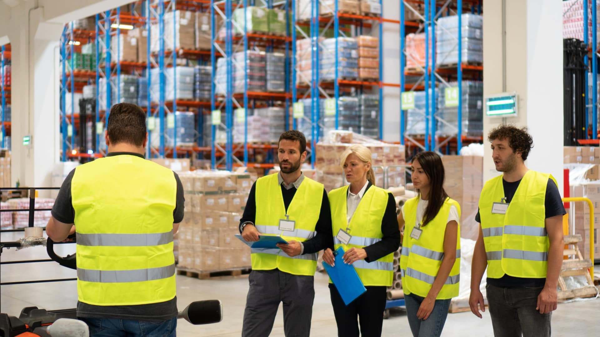A group of people in high-vis jackets doing llop training in a warehouse setting.